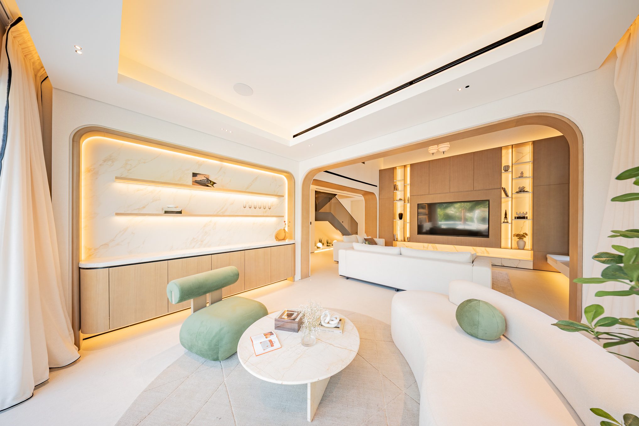 Arched living room with lit marble shelving and sage velvet chair